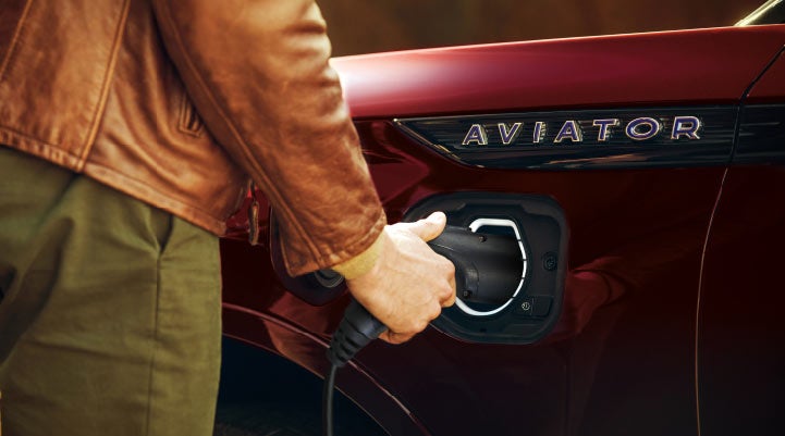 A hand is shown plugging in the charger into the charging port of a 2021 Lincoln Aviator | Bergstrom Lincoln of Neenah in Neenah WI