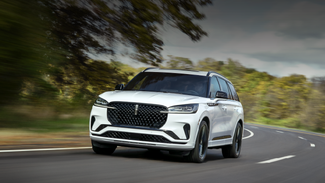 A white 2025 Lincoln Aviator® SUV is being driven down a road lined with trees. | Bergstrom Lincoln of Neenah in Neenah WI