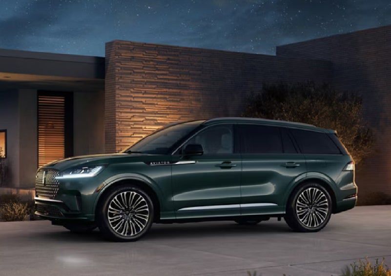 A green 2027 Lincoln Aviator® SUV is parked outside a contemporary home. | Bergstrom Lincoln of Neenah in Neenah WI