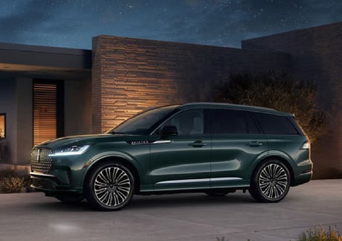 A green 2027 Lincoln Aviator® SUV is parked outside a contemporary home. | Bergstrom Lincoln of Neenah in Neenah WI