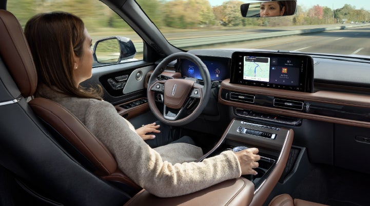 A 2027 Lincoln Aviator® SUV is being driven hands-free on a highway lined with trees. | Bergstrom Lincoln of Neenah in Neenah WI