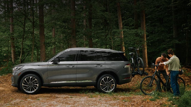 A father and son load e-bikes on a bike rack attached to a 2027 Lincoln Aviator® SUV. | Bergstrom Lincoln of Neenah in Neenah WI