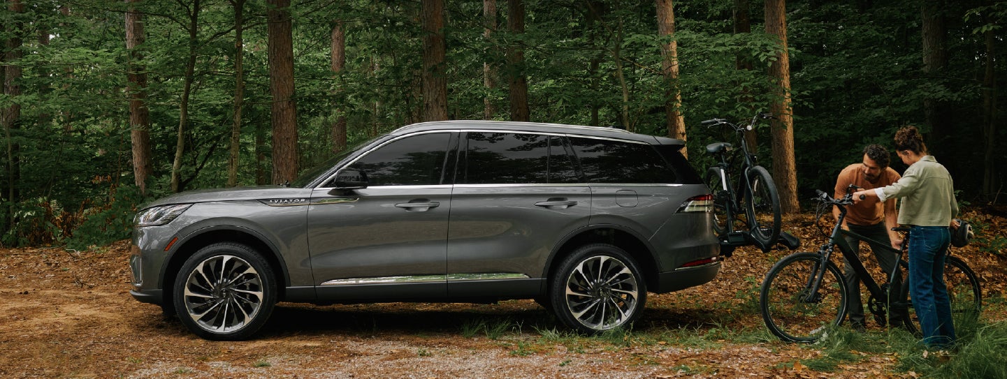 A father and son load e-bikes on a bike rack attached to a 2027 Lincoln Aviator® SUV. | Bergstrom Lincoln of Neenah in Neenah WI